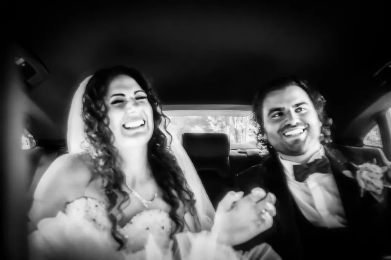 Gli sposi sorridono in auto, in bianco e nero